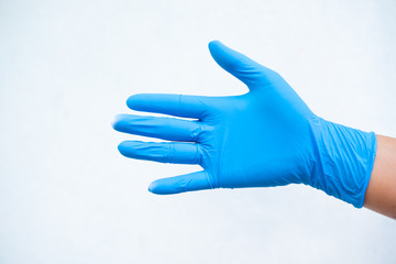 Hand put blue glove on white background.