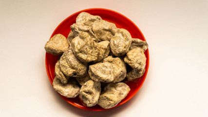 Pile of raw Asam Boi or sour plum on red bowl on white background.