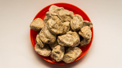 Pile of raw Asam Boi or sour plum on red bowl on white background.