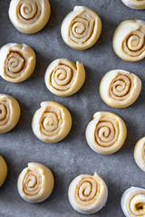 Pattern of raw cinnamon rolls, arranged on a baking tray.