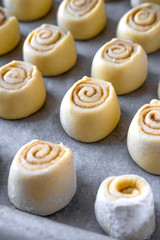 Pattern of raw cinnamon rolls, arranged on a baking tray.