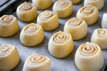 Pattern of raw cinnamon rolls, arranged on a baking tray.