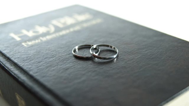 Two silver wedding rings on bible cover.