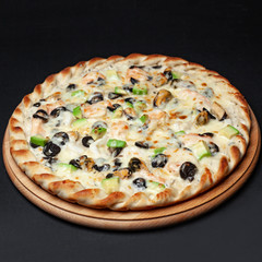 Delicious vegetarian pizza served on a wooden plate isolated on black