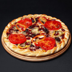 Delicious meat pizza served on a wooden plate isolated on black