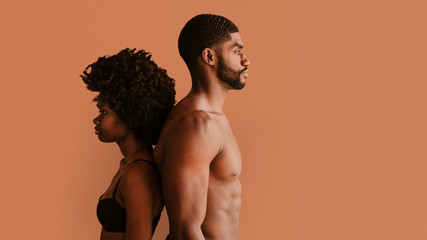 Shirtless black couple standing back to back