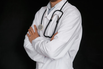 Male Doctor on a black background with a stethoscope in his hands close-up