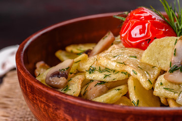Rustic potato wedges with cheese, herbs and tomato sauce on black background