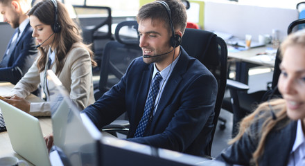 Portrait of call center worker accompanied by his team. Smiling customer support operator at work.