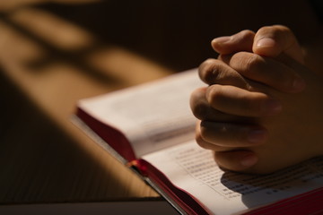 Closeup of hands and Bible, stay at home, pray to God in the dark, Covid-19
