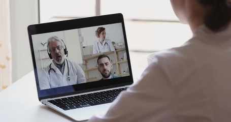 Female medical worker participate online webcam conference on laptop screen. Doctors group discuss healthcare during medic group video call virtual training webinar concept. Over shoulder closeup view - Powered by Adobe