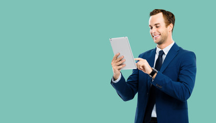 Portrait of smiling businessman using no-name tablet pc, over green marine color background. Success in business concept studio picture. Copy space for some text.
