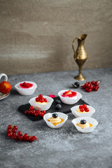 Closeup side view on sweet cute berry mini desserts on the grey background, vertical
