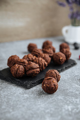 Side view on chocolate cookies oreshki nuts with condensed milk on the black board with a cup of tes, vertical