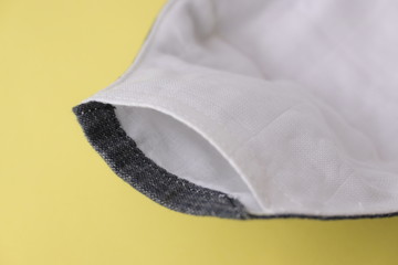 detail of cloth mask material with white salu muslin fabric soft textile, objects put on yellow background