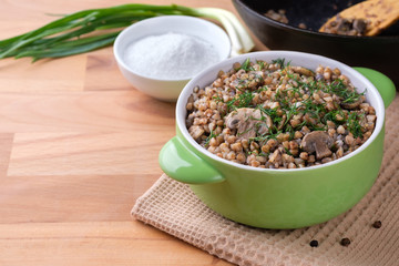 Buckwheat porridge with mushrooms, green onion and salt on the table. Copy space