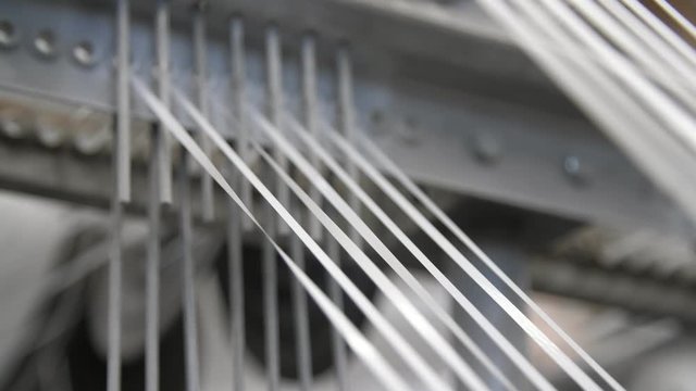 Stripes of moving white ropes on a large machine manufacturing plastic sacks 