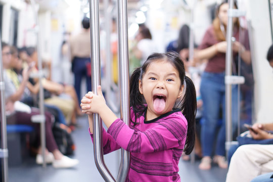 Asian Child Cute Or Kid Girl Stick Out Tongue Enjoy In Sky Train Bogey Or Electric Train With Metro Railways Or Subway And Holding Rail For Happy Travel Or Transportation Fun In City Street On Holiday