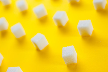 Refined sugar cubes shot on a yellow background. Background for sweets, food and drinks.