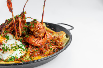 Formentera Lobster with fried potatoes, eggs and parsley in a traditional paella pan. Caldereta de bogavante de Formentera