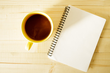 cup of hot chocolate on wooden background with notebook.  Work from home concept.