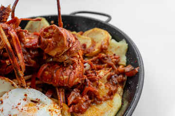 Formentera Lobster with fried potatoes, eggs and parsley in a traditional paella pan. Caldereta de bogavante de Formentera