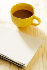 cup of hot chocolate on wooden background with notebook.  Work from home concept.