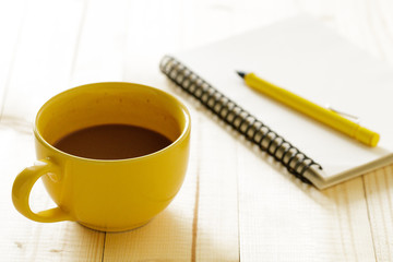 cup of hot chocolate on wooden background with notebook.  Work from home concept.