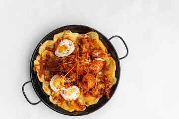 Formentera Lobster with fried potatoes, eggs and parsley in a traditional paella pan. Caldereta de bogavante de Formentera