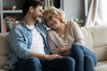 Lively cheerful mature mother enjoy communications laughing talk with grown up child millennial...