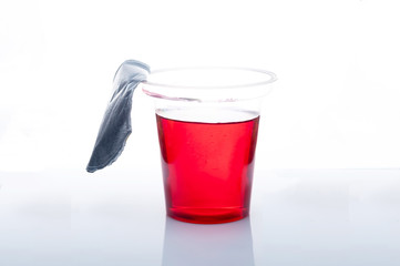 Red jelly in a transparent plastic glass not a white background. Gray gradient.