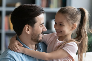 Close up image young father and little daughter sitting on couch side profile view faces, relatives people hugging look at each other with love and tender, fatherhood and happy family portrait concept