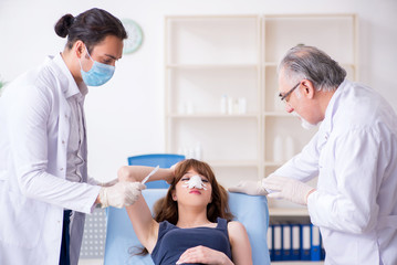 Fototapeta premium Two male doctors and young woman in plastic surgery concept