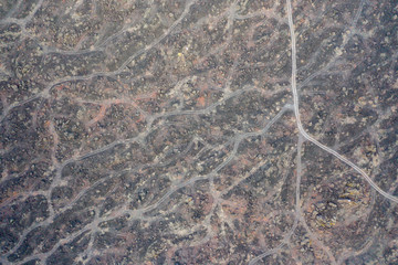 Top down aerial view of tracks running through solidified black lava flows from an active volcano