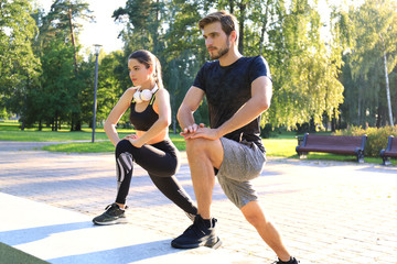 Obraz premium Happy young couple exercising together in a park.