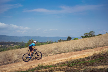 Fototapeta na wymiar Mountain biker cycling, training and going up a steep climb.