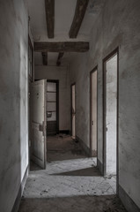 Pasillo iluminado de casa abandonada con puertas abiertas.