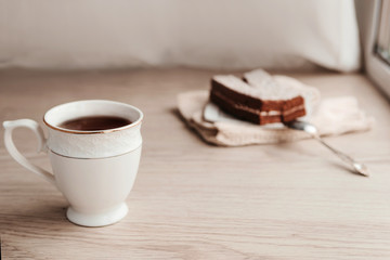 piece of cake lying on a saucer with a mug of tea