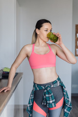 Delighted young woman drinking water after workout at home holding a glass in the hand