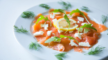 Salmon carpaccio with cheese and a lemon slice 