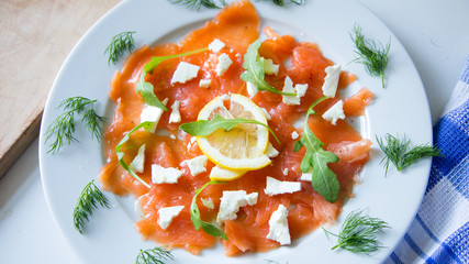 Salmon carpaccio with cheese and a lemon slice 