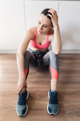 Fototapeta na wymiar Young woman resting after working out in the living room on kitchen background dressed in sportswear