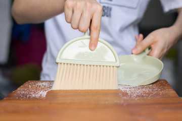 Close up woman hand cleaning table 
 by dustpan after cooking.cleaning concept.
