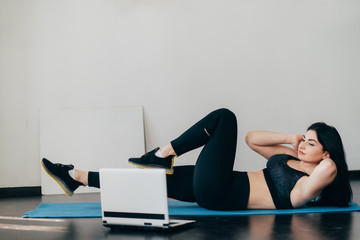 Fototapeta premium Home training, fitness, motivation concept. Young fit woman doing sport exercises with online guide in her living room.