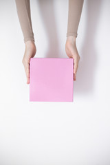 Pink parcel cardboard box in a delivery woman hands on a white background. Delivery service concept.