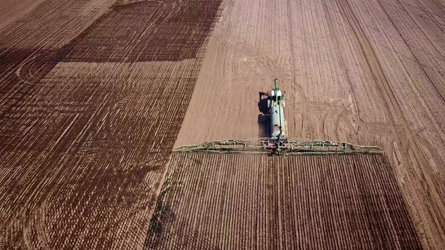 Traktor spr&uuml;ht G&uuml;lle auf Feld