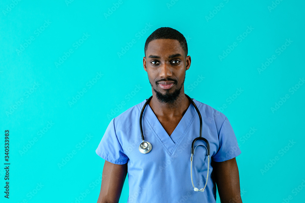 Wall mural Portrait of a serious male doctor or nurse wearing blue scrubs uniform and stethoscope, isolated on blue background