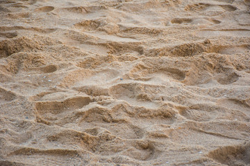 Sand near a beach. There are many footprints on it.