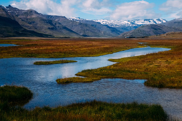 Naklejka na ściany i meble calm river in a field against the backdrop of mountains in iceland