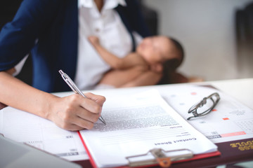 Asian businesswoman working and holding her son in arm, working from home, selective focus